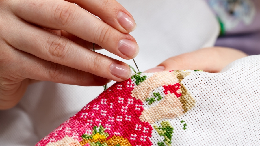 Woman hands doing a cross-stitch